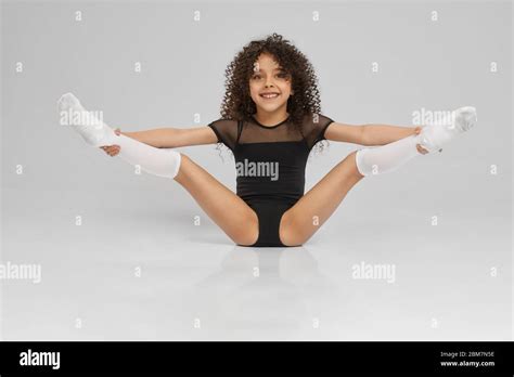 Young Female Professional Gymnast Sitting On Floor With Legs Wide Up