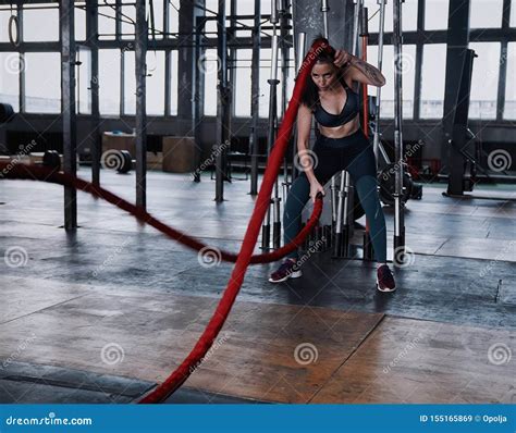 Fit Woman Using Battle Ropes During Strength Training At The Gym Stock