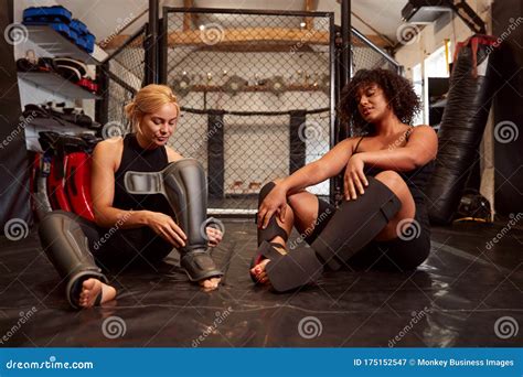 Two Female Mixed Martial Arts Fighters Putting On Protective Equipment