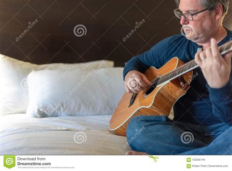 Man Sitting On Bed Playing Guitar Stock Image Image Of Strumming