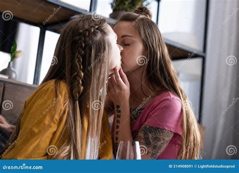 two lesbians with wine glass kissing in living room stock image