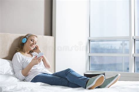 Full Length Of Relaxed Woman Listening Music In Bedroom Stock Photo