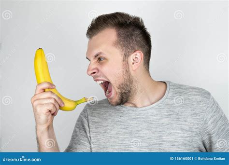Young Handsome Man Holding Fresh Banana Like A Smartphone Screaming On