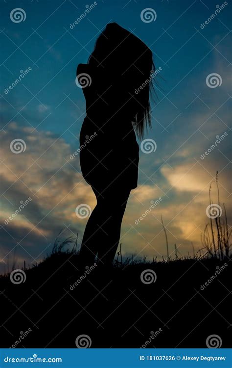 Silhouette Of A Slender Girl Against The Sky In The Evening At Sunset