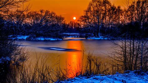 Sunset In Winter Snow River Coast Two Sun Orange Sky Reflection In