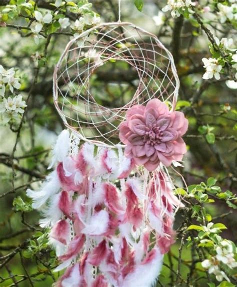 A Pink And White Dream Catcher Hanging From A Tree With Lots Of Flowers