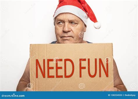 Funny Upset And Angry Mature Man In Red Christmas Santa Hat Holds Cardboard Sign With