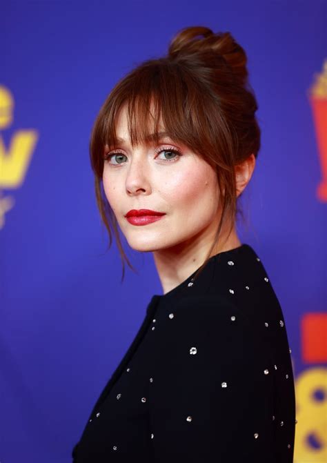 Elizabeth Olsens Curtain Bangs And Top Knot Hairstyle And Bold Red Lip
