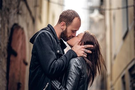 premium photo positive bearded male kissing cute brunette female on a street in an old town