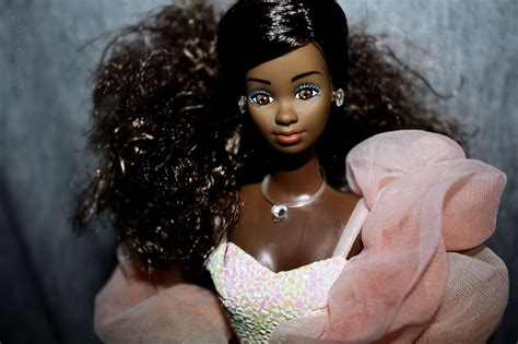 A Black Doll With Long Hair Wearing A Pink Dress