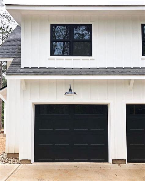 Modern Farmhouse With White Clapboard Siding Black Garage Doors And