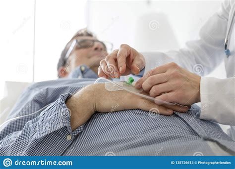 Cropped Image Of Doctor Adjusting Saline Iv Drip For Patient In