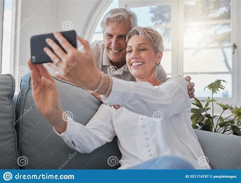 Enjoying Their An Affectionate Senior Couple Taking Selfies While Relaxing In The Living Room