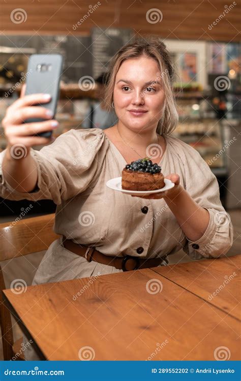 Excited Young Woman With Cake And Smartphone Taking Selfie While Having