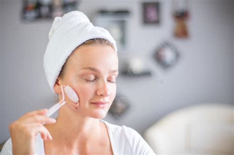 massage facial une belle femme se fait masser le visage en utilisant un rouleau facial jade