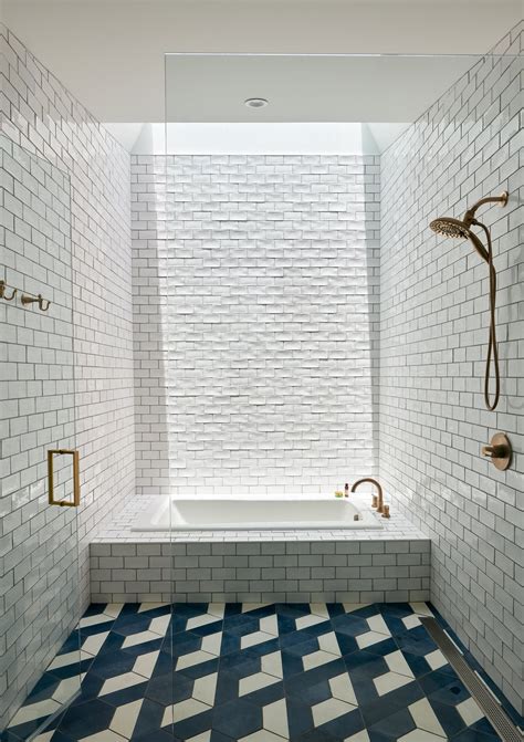 Naturally Lit White Tiled Bathroom With Brass Tapware Under A Skylight