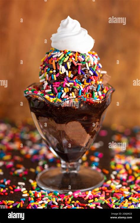 A Chocolate Ice Cream Sundae With Chocolate Syrup And Rainbow Sprinkles