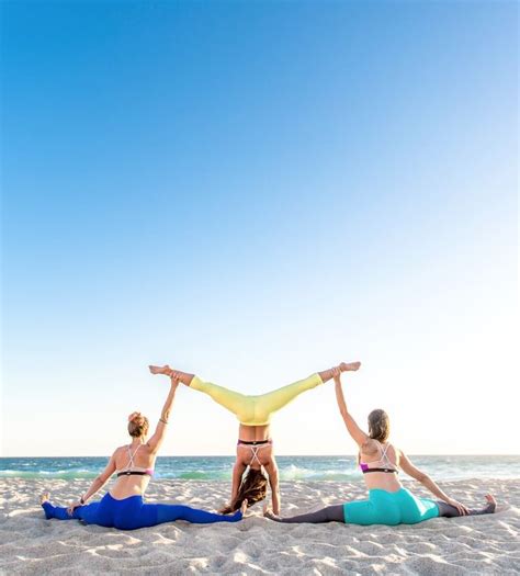 Three Women Doing Yoga Exercises On The Beach