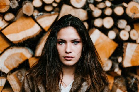 Portrait Of A Beautiful Brunette Woman With A Wooden Pile Behind Del