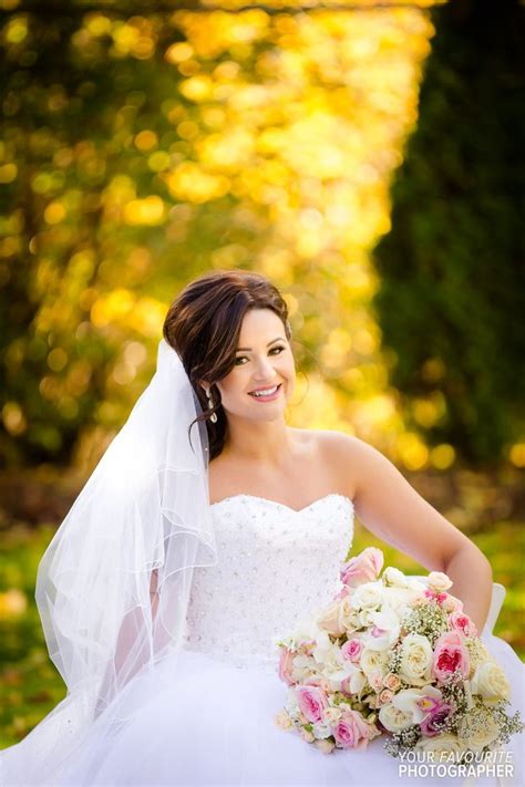 beautiful brunette bride posing with bouquet in front of autumn colours brunette bride bride