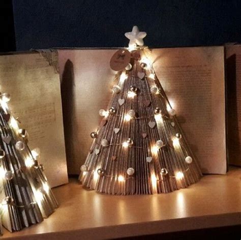Three Christmas Trees Made Out Of Books On A Shelf With Lights In The