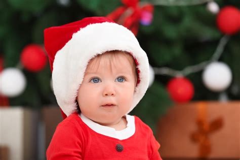 Premium Photo Cute Baby In Santa Hat Against Blurred Christmas Background