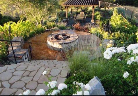 An Outdoor Fire Pit Surrounded By White Flowers