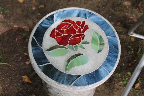 A Stained Glass Rose Sits On Top Of A Trash Can