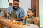 African family parents and two little daughter eating fried chicken and ...