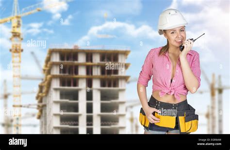 Woman In Helmet And Tool Belt Talking On Portable Radio Construction