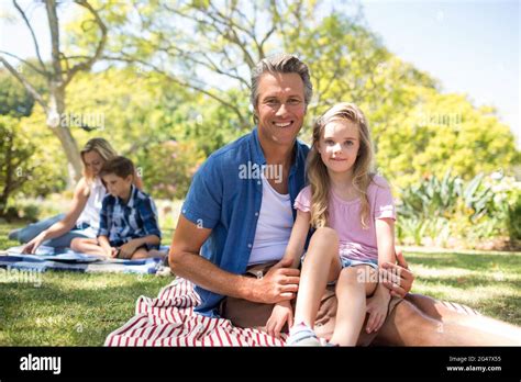 Daughter Sitting On Fathers Lap In Park Stock Photo Alamy