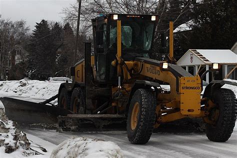 A City Snowplow Works To Clear Snow From A Residential Street On