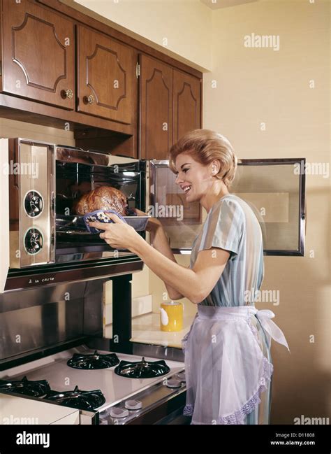 1960s Woman Housewife In Apron Oven Baking Cooking Roast In Kitchen