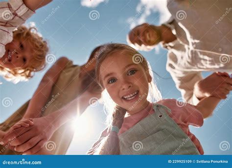 Portrait Of Adorable Little Girl Holding Parents And Brother Hands