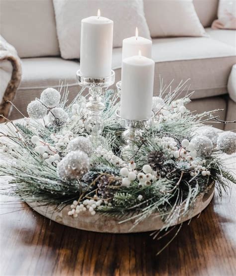 Two Candles Are Lit On Top Of A Christmas Centerpiece With Pine Cones