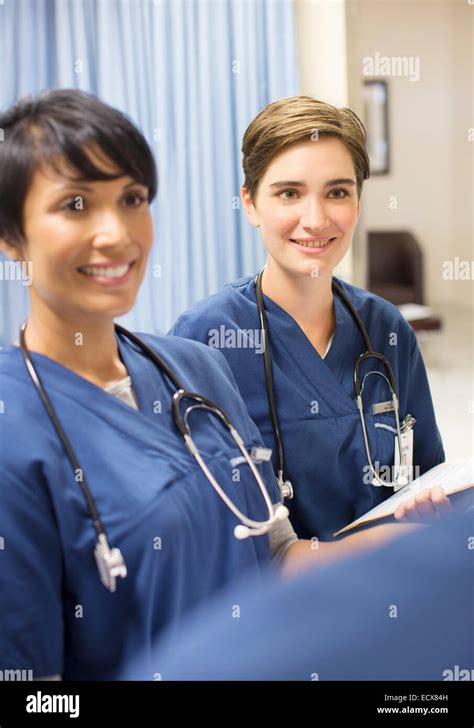 Two Smiling Doctors Wearing Scrubs With Stethoscopes Around Necks In