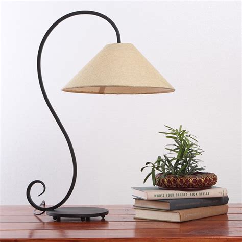 A Lamp That Is On Top Of A Table Next To Some Books And A Plant