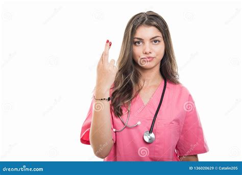 Portrait Of Beautiful Young Doctor Wearing Scrubs Showing Fingers