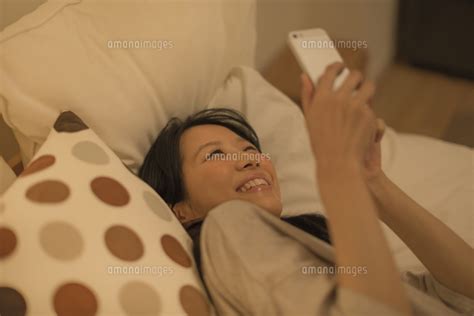 ベットに寝転んでスマートフォンを操作する女性 10367008601 の写真素材・イラスト素材｜アマナイメージズ
