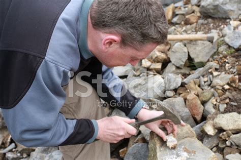 Male Geologist Scientist With Hammer Studying Rock Sample Stock Photo