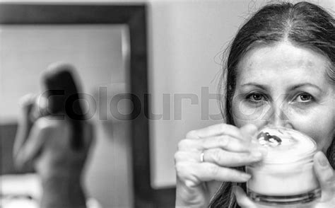 Woman In 40s Caring Of Her Beautiful Skin On The Face Standing Near Mirror In The Sleeping Room