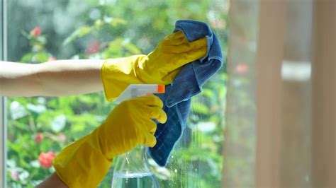 premium photo closeup of female hands in gloves cleaning window using detergent and rags house