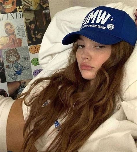 a woman laying in bed wearing a blue hat with wm on it s brim