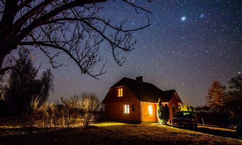 The Milky Way In Night Sky With Stars Over Wooden Country House At