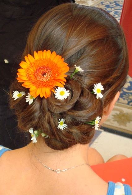 While hair flowers trended on the spring and fall 2018 runways, flora and fauna might actually be the oldest hair accessories known to mankind. beach wedding hairstyle updo with fresh flowers in orange ...
