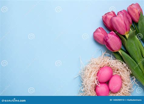 Pink Flowers Tulips With Easter Eggs On A Blue Background Stock Photo