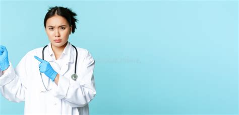 Angry Female Doctor Or Nurse Pointing Fingers At Upper Left Corner