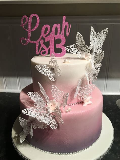 A Pink And White Cake With Butterflies On Top