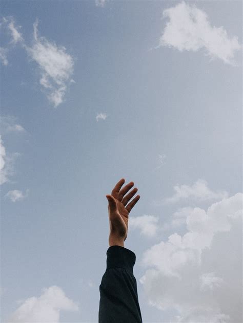 Person Raising Left Hand Under Cloudy Sky At Daytime Photo Free