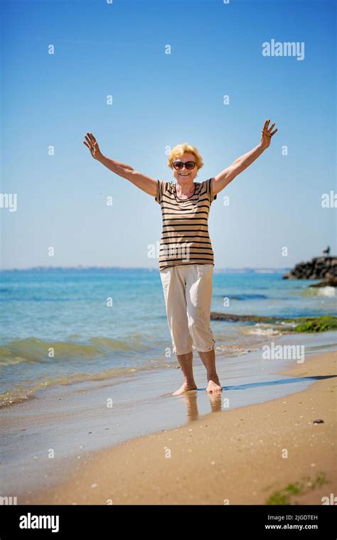Elderly Woman Walking Along The Beach And Showing Her Palm Hands